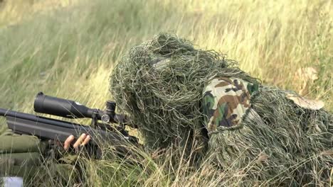 Francotirador-soldado-tendido-en-el-suelo-y-camuflaje-en-hierba.-Soldado-con-arma-pistola-y-waring-armadura-uniforme.-El-ejército-es-responsable-de-mantener-el-territorio.