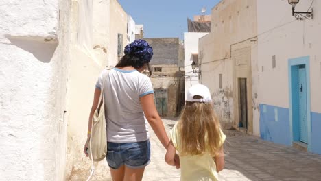 Mom-with-her-daughter-walking-by-old-town-street