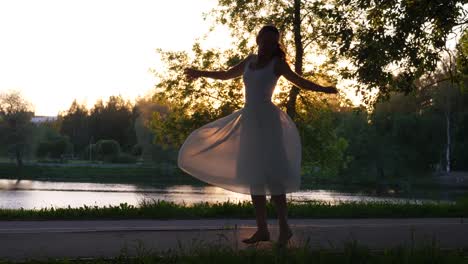 Glückliche-Frau-tanzt-im-Park-bei-Sonnenuntergang