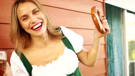 Mädchen-mit-Bier-und-Brezel,-Barkeeper-auf-dem-Oktoberfest.-Sexy-weißen-gezahnten-Lächeln,-rote-Lippen,-aufrichtige-Freude.-Bayerische-Tracht