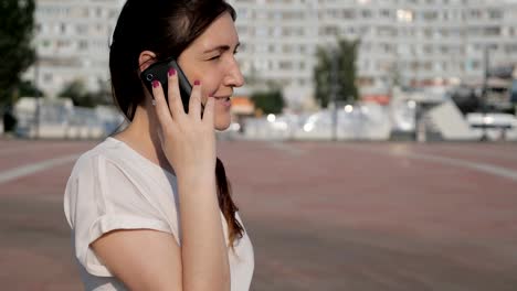 Brünette-Frau-auf-der-Straße-fällt-eine-Telefon-während-des-Gesprächs