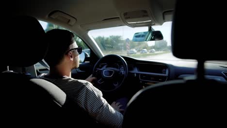 hombre-adulto-lleva-gafas-de-sol-está-sentado-dentro-de-un-automóvil-y-conducción,-movimiento-en-la-ciudad-en-día-soleado-de-verano