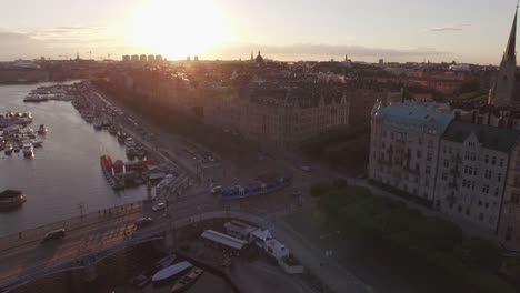 Luftaufnahme-des-Stockholmer-Stadtbild-bei-Sonnenuntergang.-Drohne-Schuss-fliegt-über-Kanal,-Straße-und-Gebäude.-Verkehr-und-Straßenbahn-Auto-vorbei,-Hauptstadt-von-Schweden