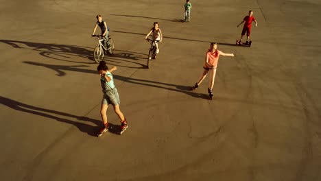 Team-von-fröhlichen-Teenager-fahren-auf-Fahrrädern,-Rollschuhen-und-Roller.-Augen-der-Vogelperspektive