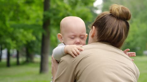 Mutter-beruhigt-verärgert-Baby-im-Park