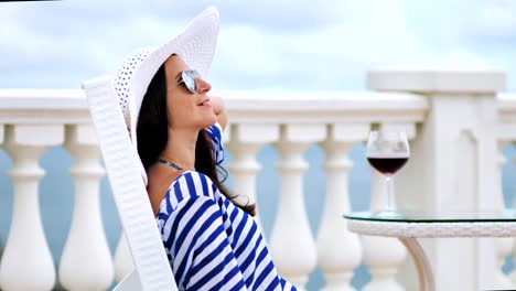 Attractive-female-tourist-enjoying-wonderful-seascape-at-embankment-with-goblet-of-red-wine