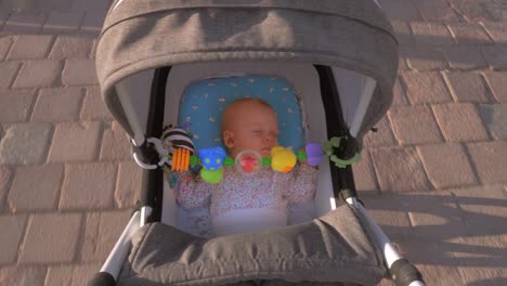 Baby-girl-sleeping-during-outdoor-walk-in-pram