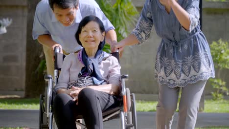 Son-and-daughter-in-law-looking-after-elderly-mother-in-backyard