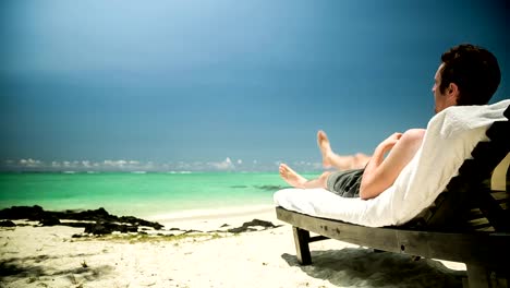 Man-relaxing-in-sun-chair-at-beach