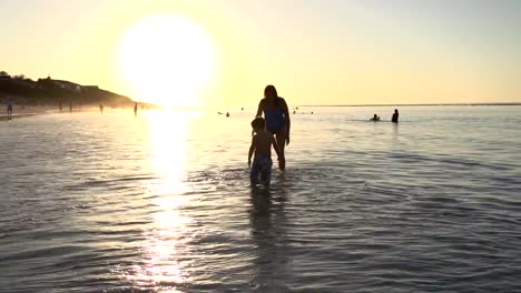 Mutter-und-Kind-spielen-am-Strand-auf-silhouette-bei-Sonnenuntergang,-Cape-Town