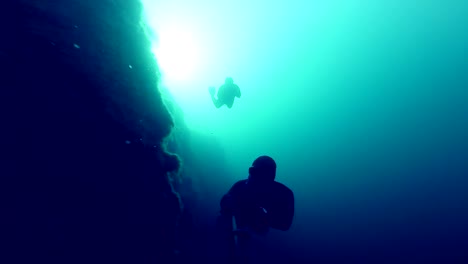 Deep-Freedivers-Erkunden-einer-Seite-von-einem-Unterwasser-Klippe