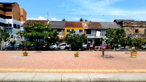 Calle-tranquila-con-viejas-casas-adosadas,-personas-paseando-en-día-de-verano-caliente