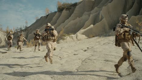 Squad-of-Fully-Equipped,-Armed-Soldiers-Running-in-the-Desert.-Show-Motion.