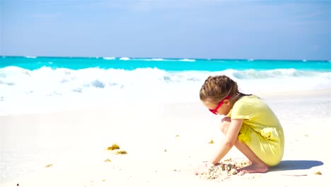 Entzückende-kleine-Mädchen-spielen-am-Strand-mit-sand