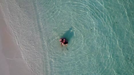 v03999-vuelo-drone-vista-aérea-de-Maldivas-playa-2-personas-pareja-hombre-mujer-amor-romántico-en-la-isla-de-paraíso-tropical-soleado-con-cielo-azul-aqua-agua-mar-4k