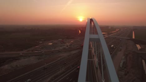 Nuevo-puente-construido-sobre-una-carretera-con-tráfico,-en-puesta-de-sol