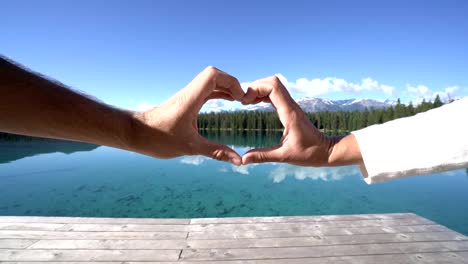 Closed-up-on-couple-hands-making-a-heart-shape-frame-by-the-lake