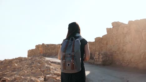 Linda-chica-con-mochila-paseos-por-ruinas-antiguas.-Turista-europeo-bastante-explora-la-fortaleza-de-Masada-Israel.-4K