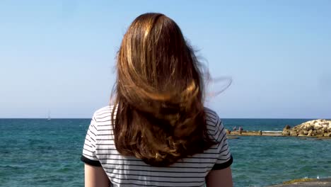 Chica-con-pelo-largo-rojo-en-la-playa,-brisa-juega-con-el-pelo,-tiro-durante-el-día.