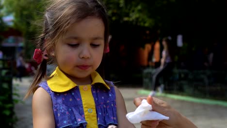 Una-mujer-joven-es-limpiar-la-cara-de-su-hija.