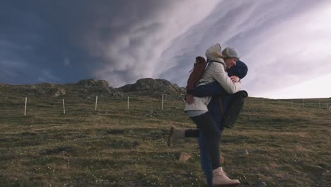 Jóvenes-amantes-de-la-pareja-abrazándose-en-campo-sobre-fondo-de-nubes-dramáticas-épicas,-cámara-lenta