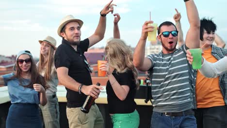 Creative-young-people-dancing-and-having-fun-with-raised-arms-at-rooftop-party