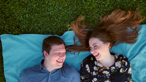 Happy-young-adult-couple-lying-on-the-grass-over-sunset