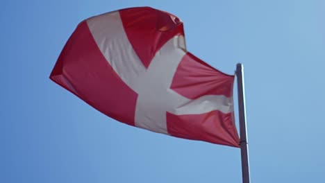 Bandera-de-Dinamarca-ondeando-en-el-viento-con-cielo-azul