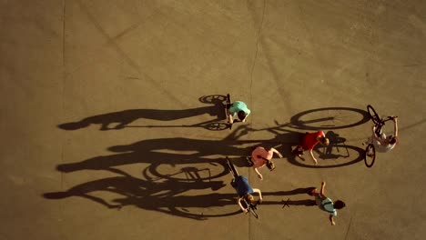 Los-niños-ciclismo,-patinaje-y-scooter-sombras-largas.-Vista-superior,-cámara-lenta