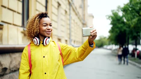 Fröhliche-Mischlinge-Mädchen-macht-Videoanruf,-sprechen-und-lachen-Holding-Smartphone-und-mit-Blick-auf-den-Bildschirm.-Moderne-Technologie,-Kommunikation-und-Jugendliche-Konzept.