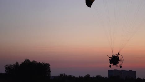 El-piloto-de-un-parapente-vuela-desde-la-cámara-poco-a-poco-alejándose-en-la-distancia-contra-el-hermoso-cielo-al-atardecer