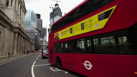 Iconic-red-double-decker-bus-passing-during-morning-rush-hour-in-the-business-district-London,-UK.