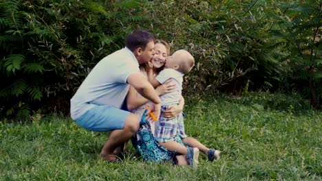 Mama,-Papa-und-Sohn-Spaß-haben-und-spielen-auf-dem-Rasen-im-Park-auf-einem-grünen-Hintergrund.-Sie-lachen,-umarmen-und-küssen.-Vintage-Verarbeitung.