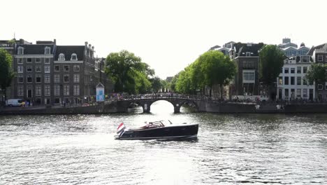 Oldtimer-Boot-segelt-in-ikonische-Kanal-mit-traditionellen-Brücke-in-Amsterdam,-Holland-Europa