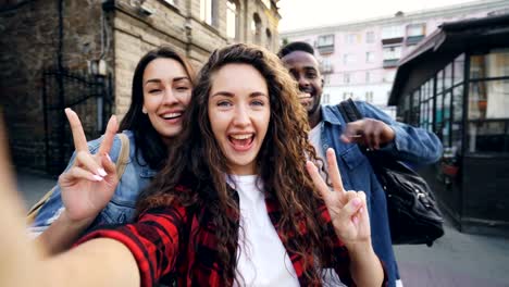 Point-Of-View-erschossen-fröhliche-Mädchen-und-Jungs-multiethnische-Gruppe-nehmen-Selfie-Kamera-halten-und-posiert-im-freien-während-Ferien-in-schönen-Stadt.-Tourismus-und-Fotografie-Konzept.