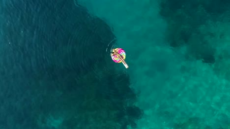 Vista-aérea-de-la-mujer-flotando-en-la-piruleta-inflable-en-la-isla-de-Atokos,-Grecia.