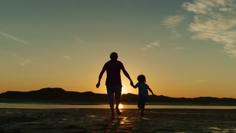 Silueta-del-padre-y-del-hijo-corriendo-juntos-en-la-playa