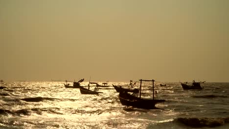 Una-gran-cantidad-de-pequeños-barcos-de-pesca-en-el-sudeste-asiático-está-en-el-puerto-pesquero-de-los-aldeanos.-La-luz-dorada-refleja-el-agua-durante-la-puesta-del-sol.