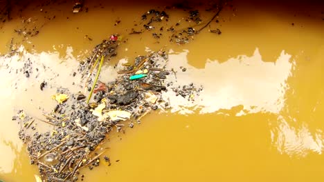 Black-coals-and-rubish-float-in-brown-water-with-reflections-holy-river-Ganga-Manikarnika-Ghat-cremation-place