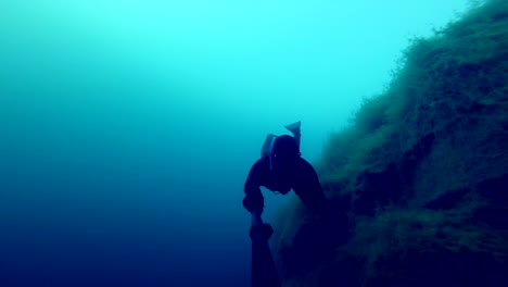 Freedivers-explorar-un-lado-de-un-submarino-del-acantilado-en-una-cantera