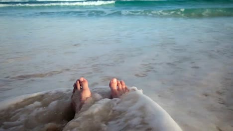 Girl-Sitting-on-the-Beach-and-Getting-her-Feet-Wet