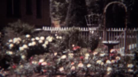 1939:-Woman-gardening-rose-flowers-front-yard-with-white-bonnet.