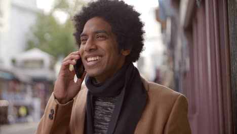 Young-Man-Using-Phone-As-He-Walks-Along-Busy-City-Street