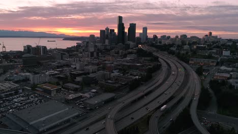 Aerial-Floating-Over-City-with-Sunset-Colors-on-Ocean-Water-and-Mountain-Range