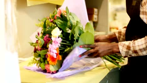 Female-florist-preparing-flower-bouquet-in-flower-shop-4k