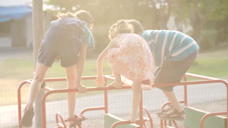 Drei-Kinder-spielen-auf-einem-öffentlichen-Spielplatz-während-des-Sonnenuntergangs