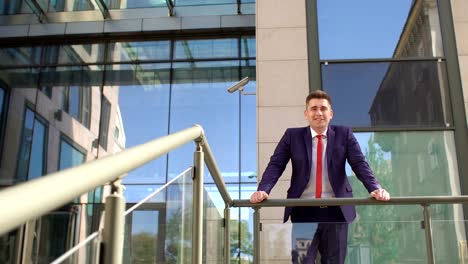 Businessman-is-leaning-on-railing-near-building.