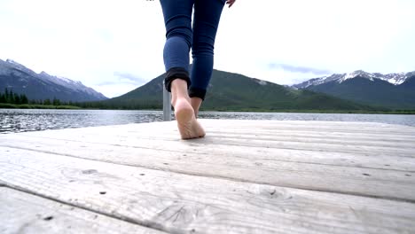 Woman's-feet-walking-on-jetty-above-lake,-Canada