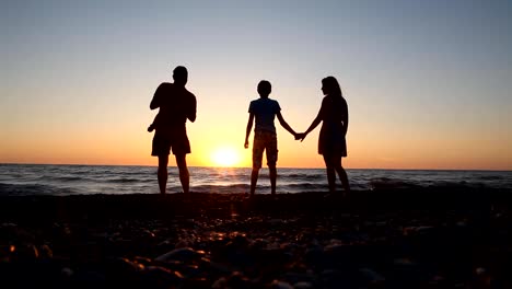 Familie-Silhouette-bei-Sonnenuntergang-in-der-Nähe-von-dem-Meer-Mutter-Vater-Kinder