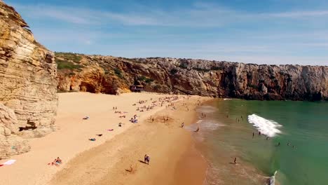 Happy-people-rest-on-a-beautiful-sandy-beach-in-Portugal,-Praia-do-Beliche,-Sagres,-aerial-view